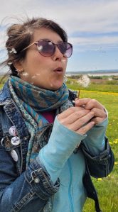 Nadine blows a dandelion.